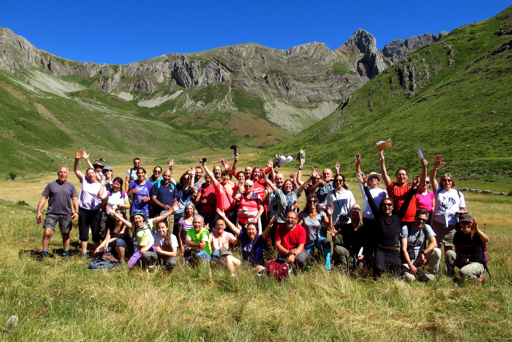 Nutrido grupo de asistentes a las jornadas geológicas de la cantábrica leonesa GeoLaciana 2022 saluda a la cámara en el valle de Fonfría (La Riera de Babia), en un circo glaciar rodeado de montañas y cubierto por los pastos de verano